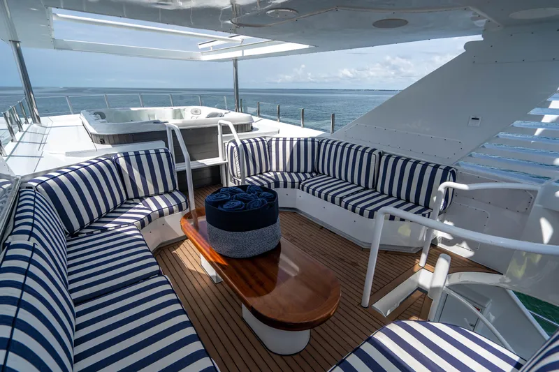 Quantum Yacht Photos Pics Luxurious 1989 Broward Tri-Deck yacht with striped seating and ocean view.
