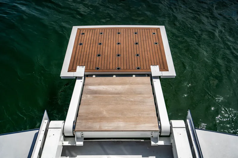 Quantum Yacht Photos Pics Broward Tri-Deck 1989 yacht swim platform with wooden decking over water.