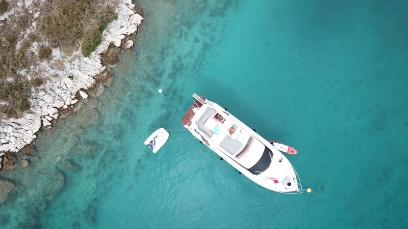  Yacht Photos Pics Aerial view of 2020 Ferretti Yachts 450 in clear turquoise water near rocky shore.