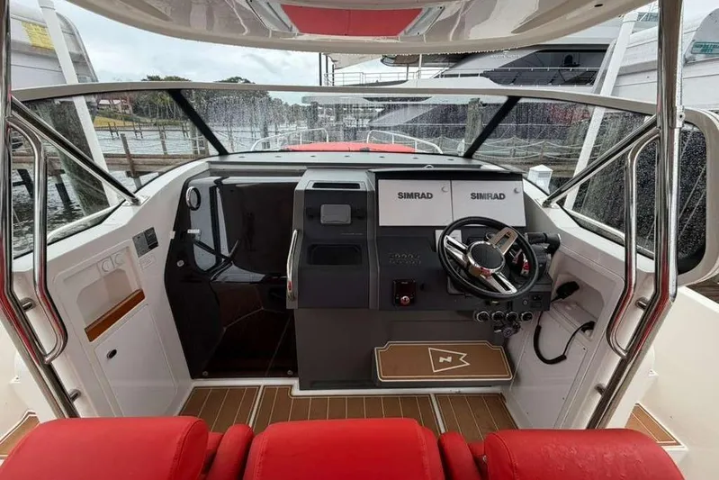 Dirty Money Yacht Photos Pics Interior view of 2021 Nimbus T-11 boat cockpit with red seating and navigation equipment.