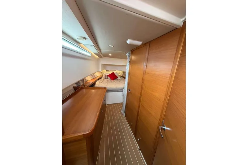 Dirty Money Yacht Photos Pics Luxurious interior of 2021 Nimbus T-11 boat with wood paneling and cozy bed.