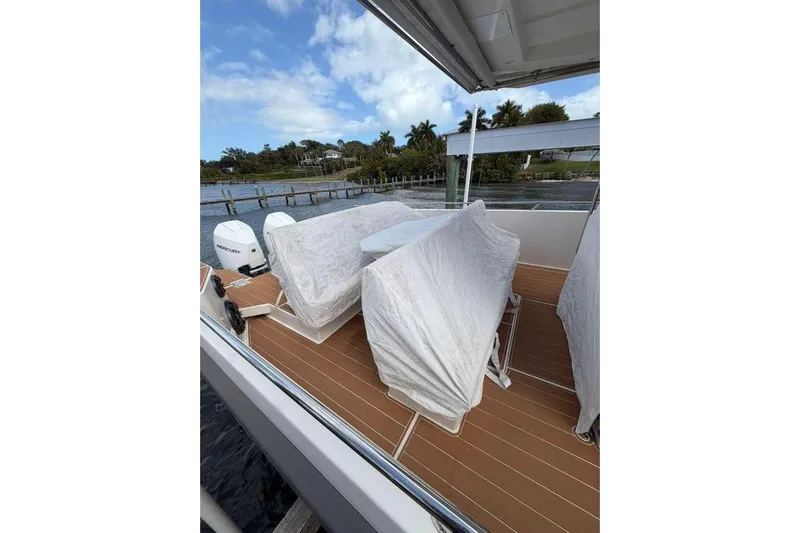 Dirty Money Yacht Photos Pics Covered seating area on a 2021 Nimbus T11 boat, docked by a scenic waterfront.