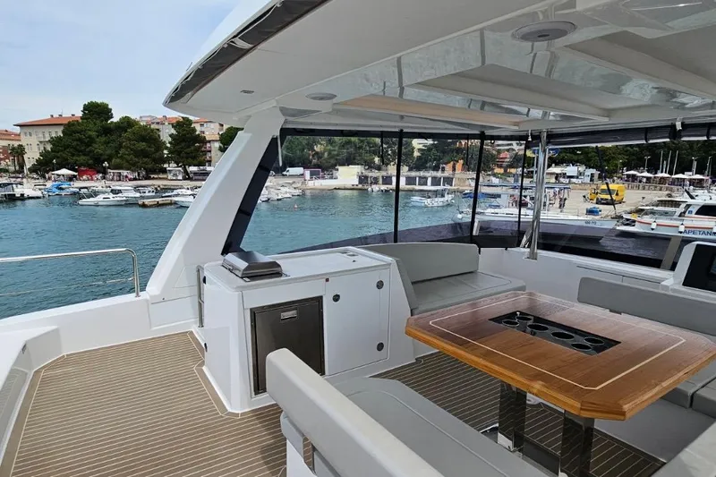  Yacht Photos Pics 2023 Leopard 40 Powercat yacht interior with seating and table, docked at a marina.