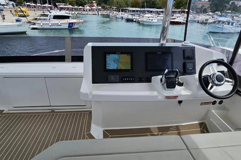  Yacht Photos Pics 2023 Leopard 40 Powercat helm with navigation screens and steering wheel, docked at marina.