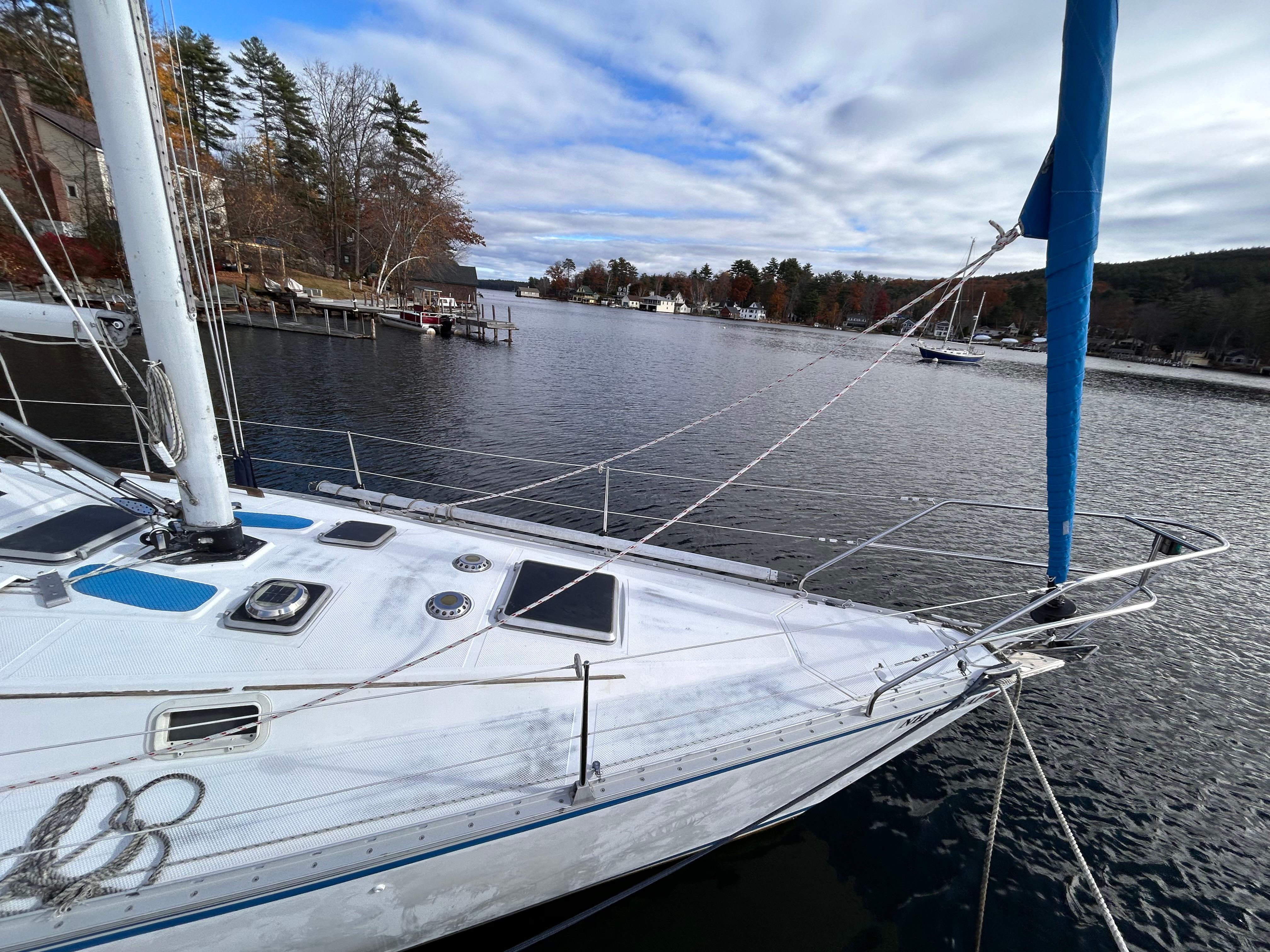 1983 Hunter 34 sailboat docked on a serene lake with a scenic backdrop.