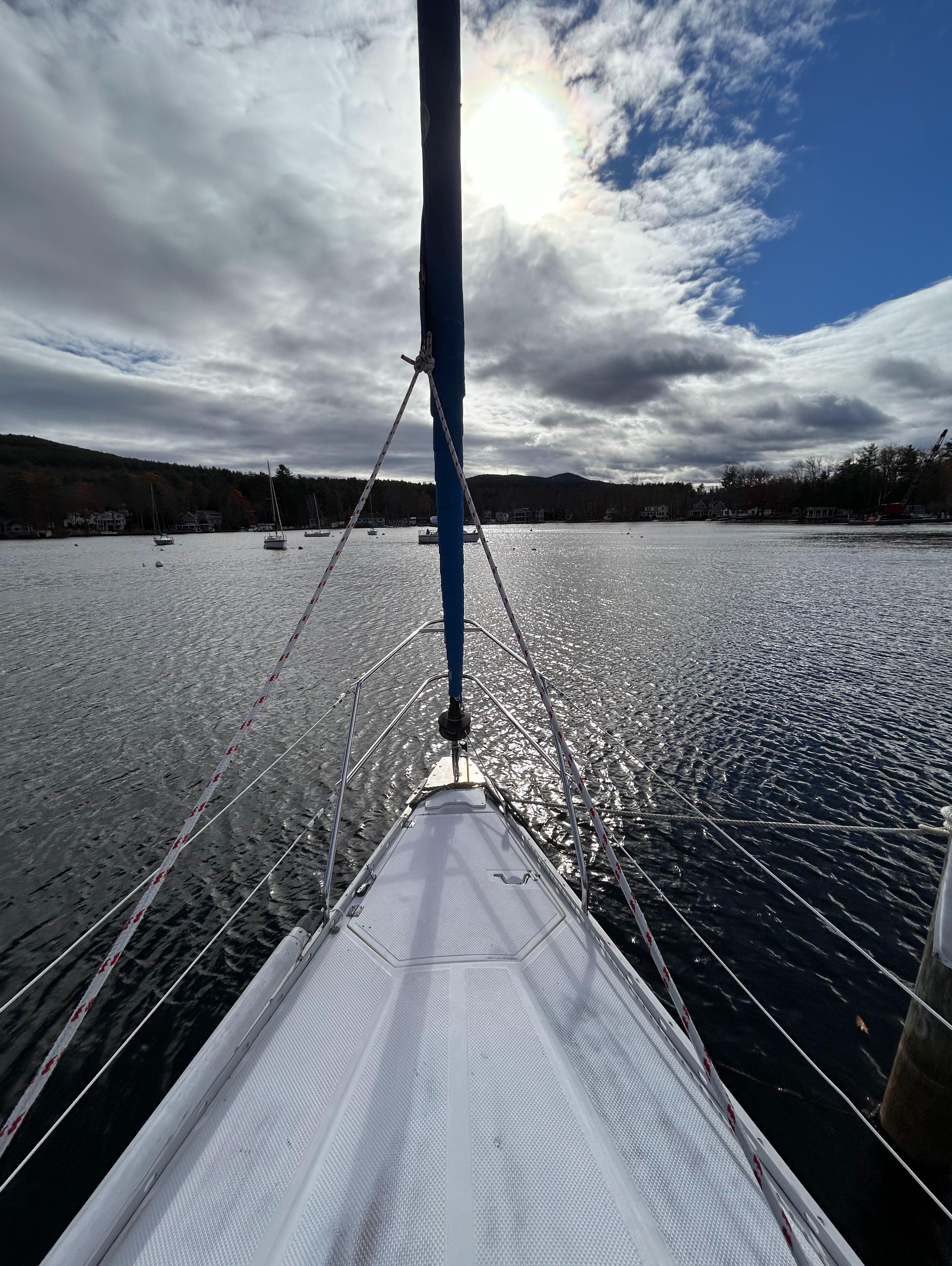 1983 Hunter 34 sailboat on a serene lake under a partly cloudy sky.