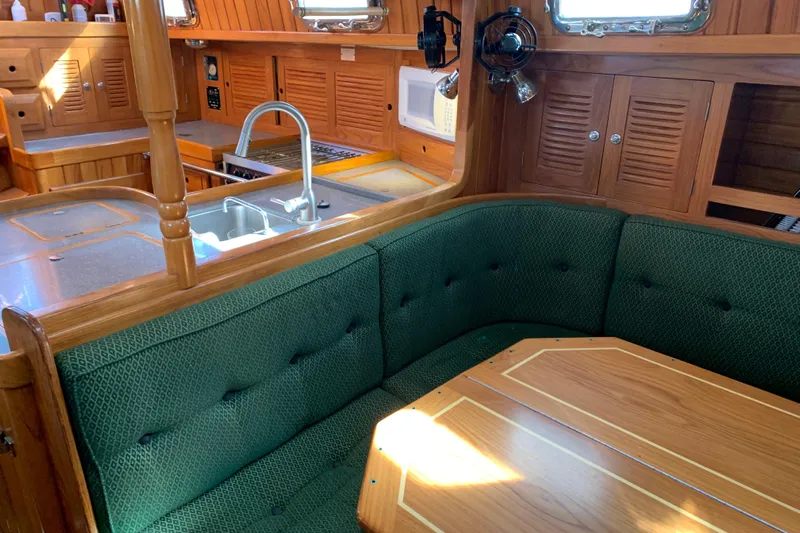 Elation Yacht Photos Pics Interior of 2004 Cabo Rico 42 Pilot yacht with green seating and wooden cabinetry.