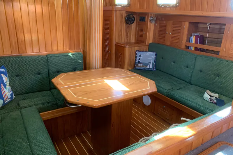 Elation Yacht Photos Pics Interior of 2005 Cabo Rico 42 sailboat with green seating and wooden table.