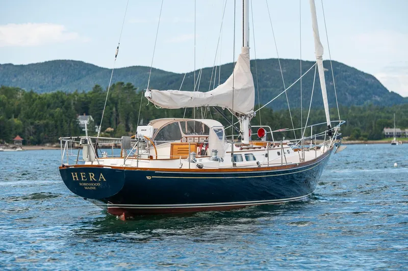 Hera Yacht Photos Pics Hinckley Sou'wester 42 Sloop, 1994, sailing on calm waters with scenic mountain backdrop.
