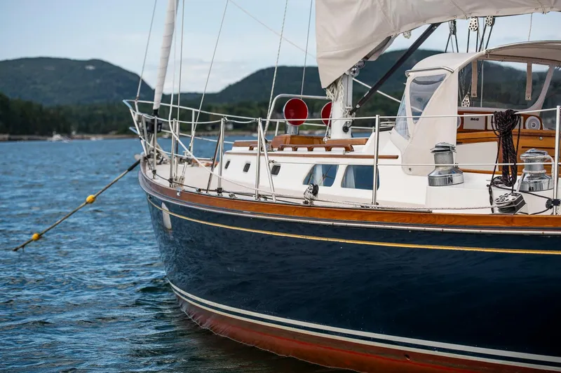 Hera Yacht Photos Pics Hinckley Sou'wester 42 Sloop, 1994, sailing on calm waters with scenic mountain backdrop.