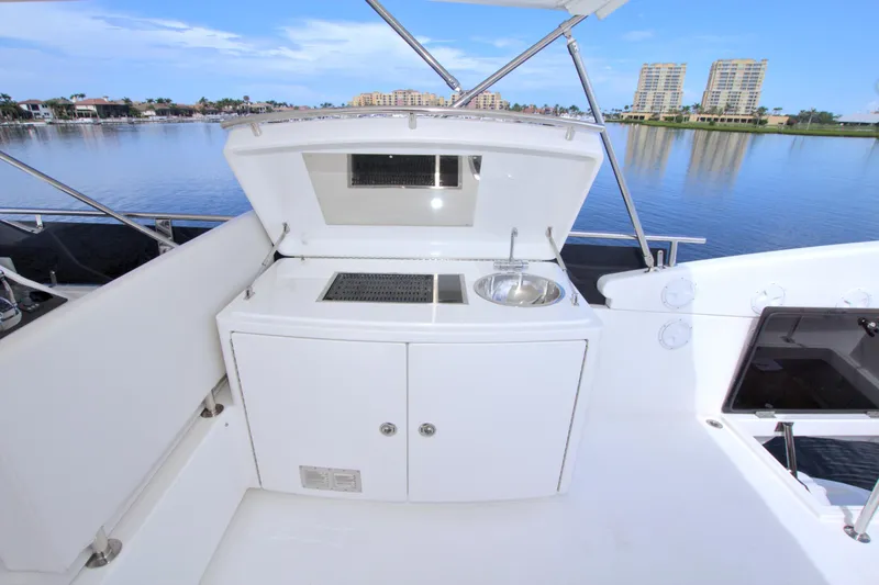 Wanderlust Yacht Photos Pics Outdoor kitchenette on a 2015 Dyna 60 yacht with sink and grill, overlooking serene waterfront.
