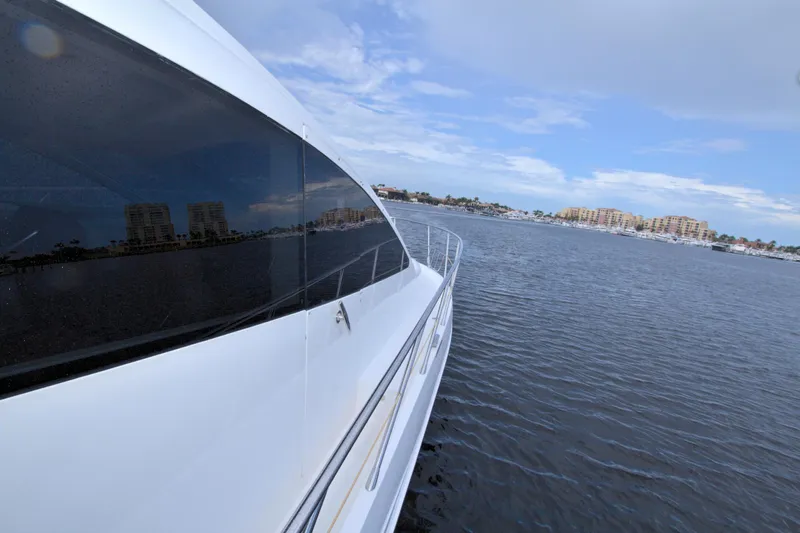 Wanderlust Yacht Photos Pics Luxury yacht Dyna 60 cruising on a calm sea, cityscape in the background.