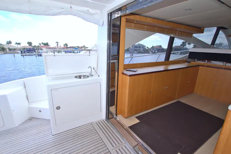 Wanderlust Yacht Photos Pics Luxurious 2015 Dyna 60 yacht interior with wooden cabinetry and outdoor sink, overlooking marina.