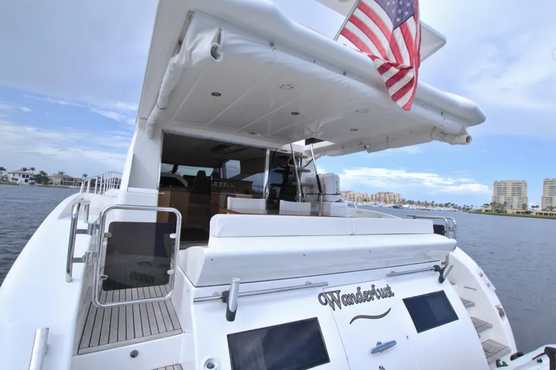 Wanderlust Yacht Photos Pics Luxury yacht Dyna 60, 2015 model, with American flag, docked near waterfront buildings.