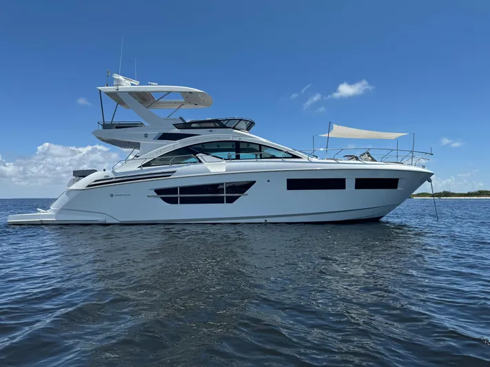 The 7 C's Yacht Photos Pics 2021 Cruisers Yachts 60 Cantius Flybridge on calm water under clear blue sky.