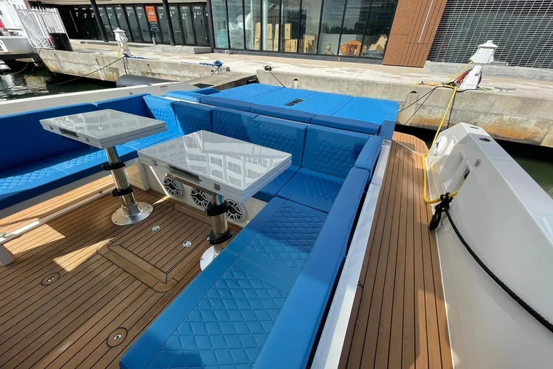  Yacht Photos Pics 2021 De Antonio Yachts Express with blue seating and wooden deck, docked at marina.