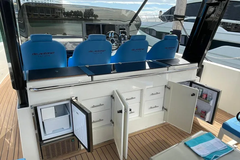 Yacht Photos Pics 2021 De Antonio Yachts Express interior with open cabinets and blue seating.
