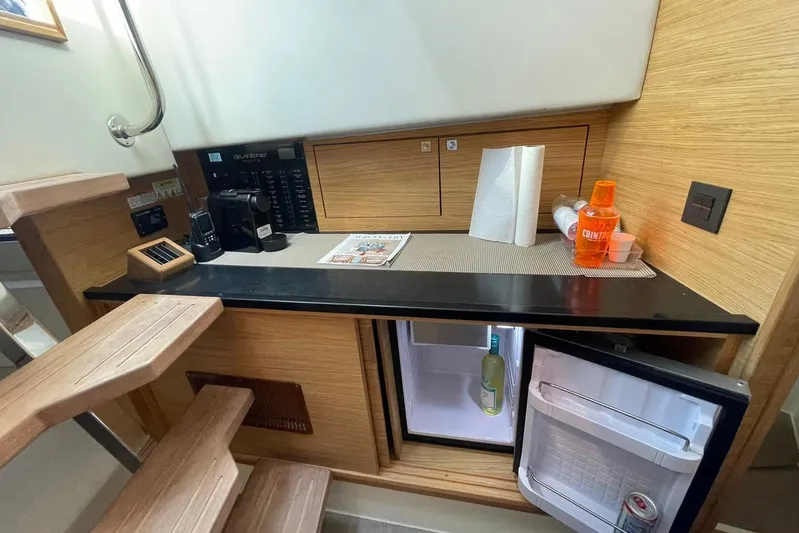  Yacht Photos Pics 2021 De Antonio Yachts Express interior with kitchenette, mini fridge, and wooden stairs.