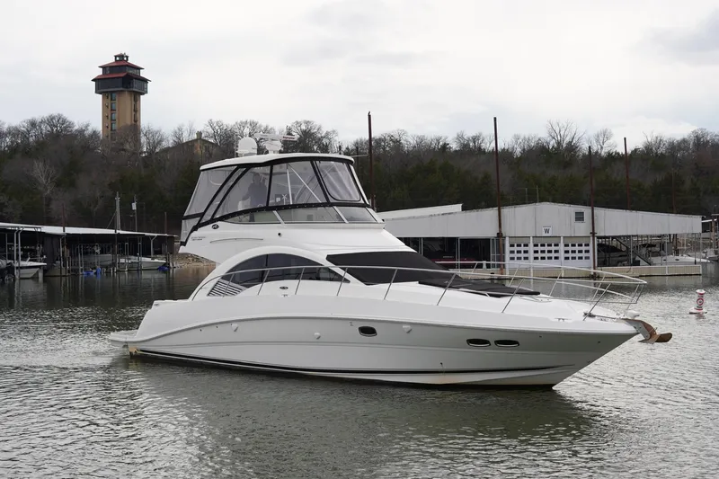  Yacht Photos Pics 2009 Sea Ray 47 Sedan Bridge yacht docked in a marina with a tower in the background.