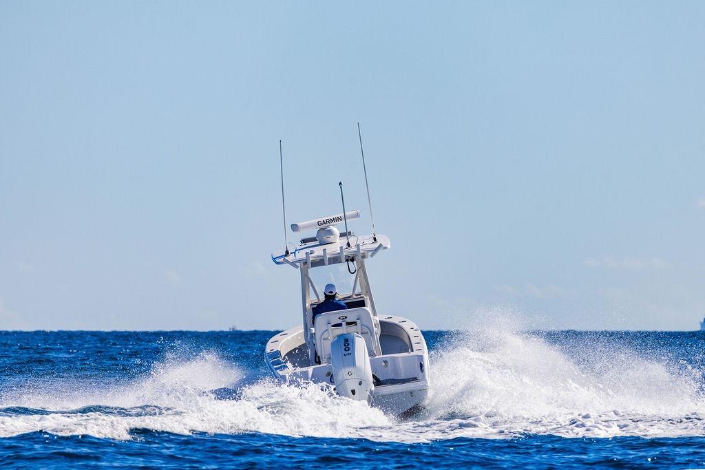 2026 Reef Runner 230 boat navigating ocean waves under clear blue sky.