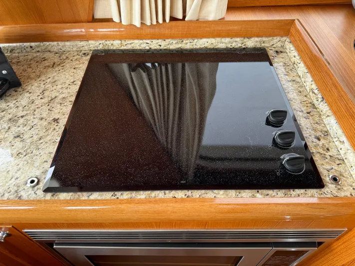 Hezitation Yacht Photos Pics Stovetop on 2009 Grand Banks 45 Eastbay SX yacht, granite countertop, wooden cabinetry.