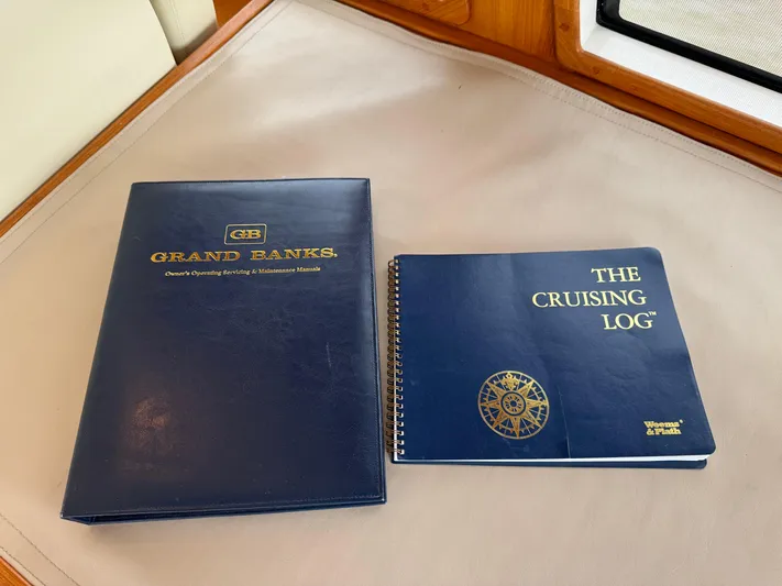 Hezitation Yacht Photos Pics Blue Grand Banks manual and cruising logbook on a boat's interior surface.