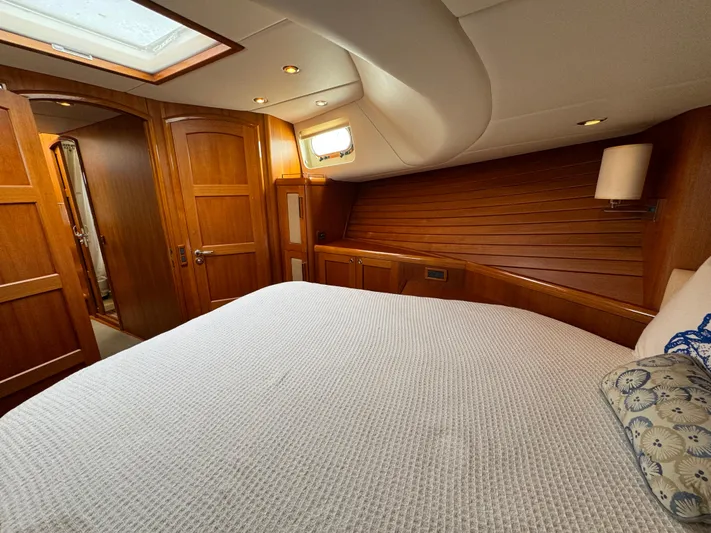 Hezitation Yacht Photos Pics Luxurious cabin interior of 2009 Grand Banks 45 Eastbay SX yacht, featuring wood paneling and cozy bedding.