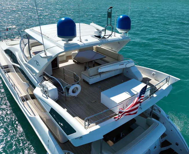 Emma Yacht Photos Pics Luxury 2014 Azimut 70 yacht on clear blue water, featuring spacious deck and American flag.
