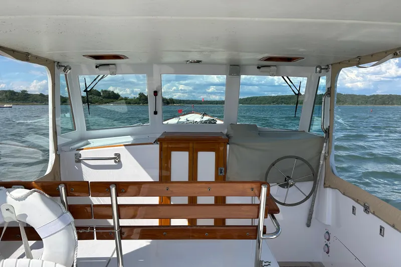 Nellie Yacht Photos Pics 1995 Holland Pettegrow Cruiser interior with wooden accents, steering wheel, and scenic water view.