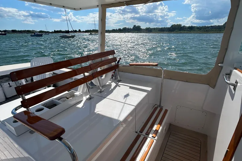 Nellie Yacht Photos Pics 1995 Holland Pettegrow Cruiser interior with wooden seating, overlooking a scenic water view.