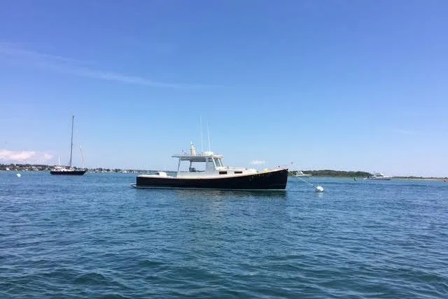 Nellie Yacht Photos Pics 1995 Holland Pettegrow Cruiser on calm blue water under clear sky.