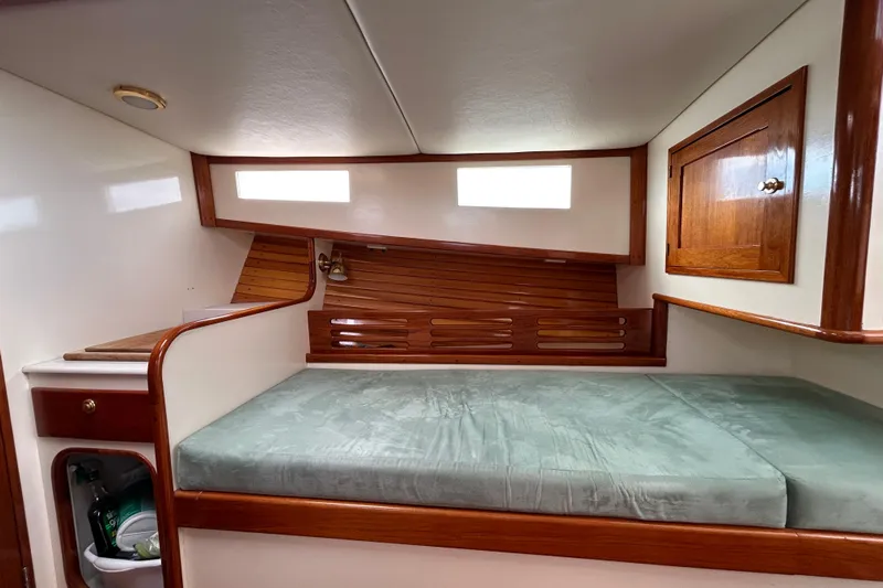 Nellie Yacht Photos Pics Cozy cabin interior of 1995 Holland Pettegrow Cruiser with wooden accents and cushioned bed.