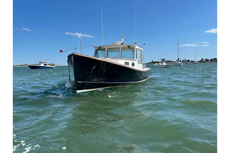 Nellie Yacht Photos Pics 1995 Holland Pettegrow Cruiser on water, clear sky, other boats in background.