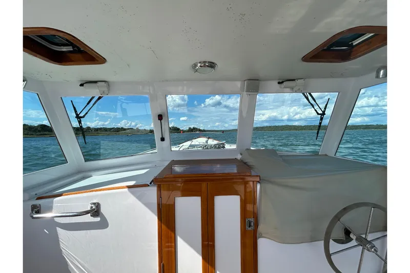 Nellie Yacht Photos Pics Interior view of 1995 Holland Pettegrow Cruiser, showcasing helm and scenic waterway.