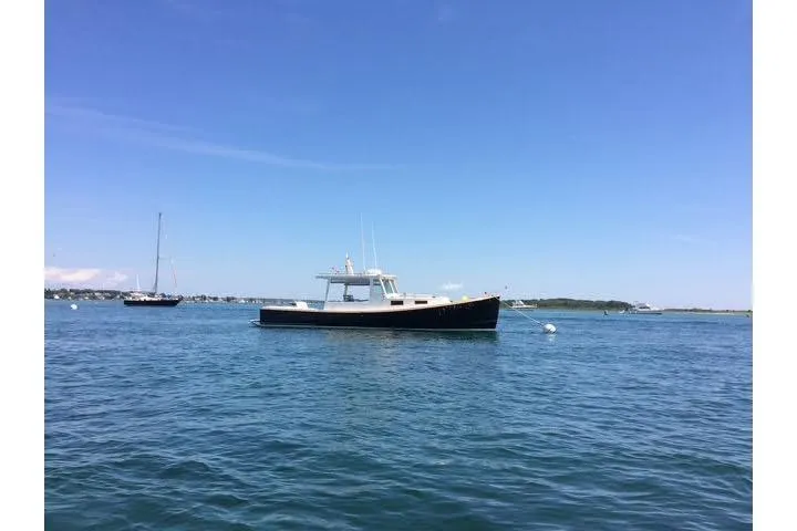 Nellie Yacht Photos Pics 1995 Holland Pettegrow Cruiser on calm blue water under clear sky.