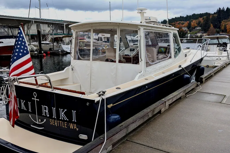 Kikiriki Yacht Photos Pics 2007 MJM 34z Downeast boat docked, displaying American flag, Seattle marina backdrop.