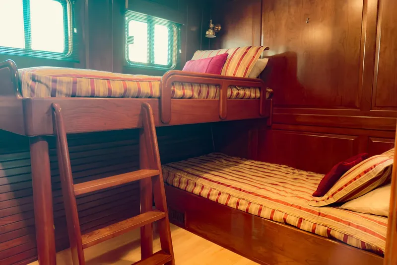 North Yacht Photos Pics Cozy yacht cabin with wooden bunk beds, striped bedding, and warm lighting, Darling Yachts 2002 model.