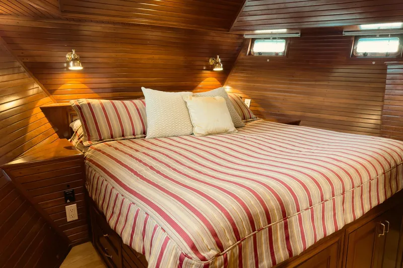 North Yacht Photos Pics Cozy cabin bedroom in 2002 Darling Yachts Custom Aluminum, featuring wood paneling and striped bedding.