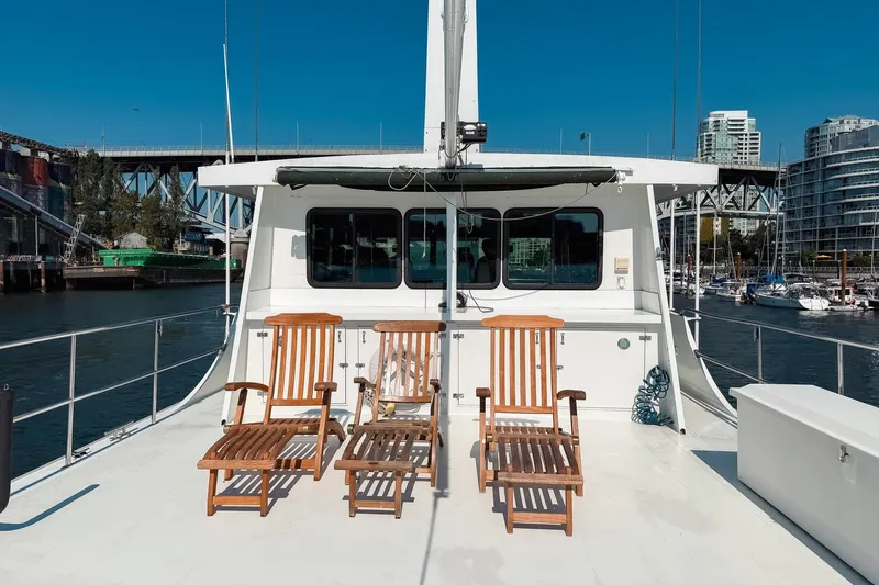 North Yacht Photos Pics Deck of 2002 Darling Yachts Custom Aluminum with wooden chairs, cityscape in background.