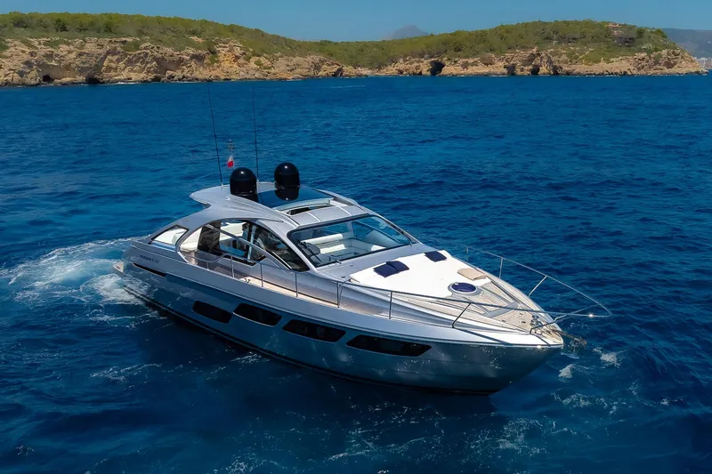 Polar Yacht Photos Pics 2023 Pershing 5x yacht cruising in clear blue waters near a rocky coastline.