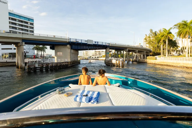  Yacht Photos Pics 2024 Solaris Power 52 Open yacht cruising under a bridge with two people relaxing onboard.