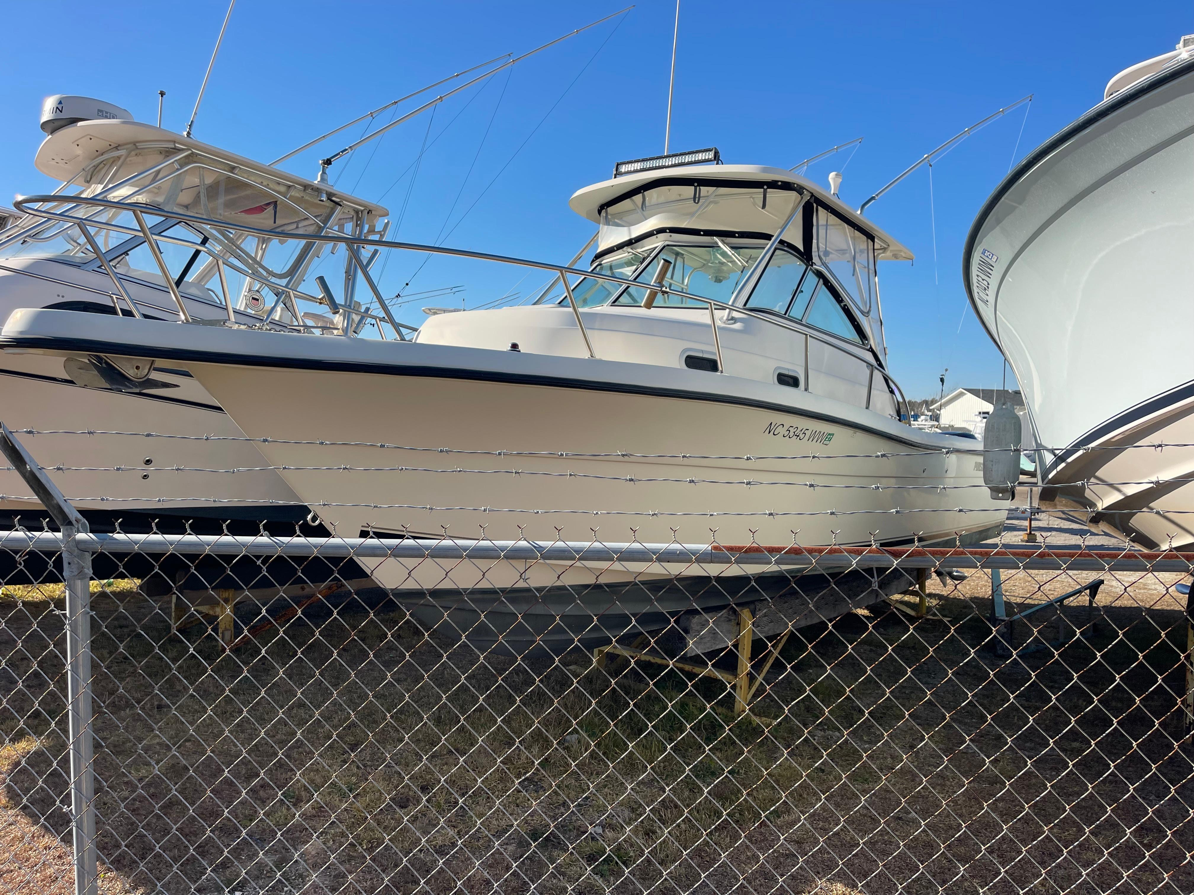 2003 Pursuit 2870 Walkaround boat on display behind a chain-link fence.