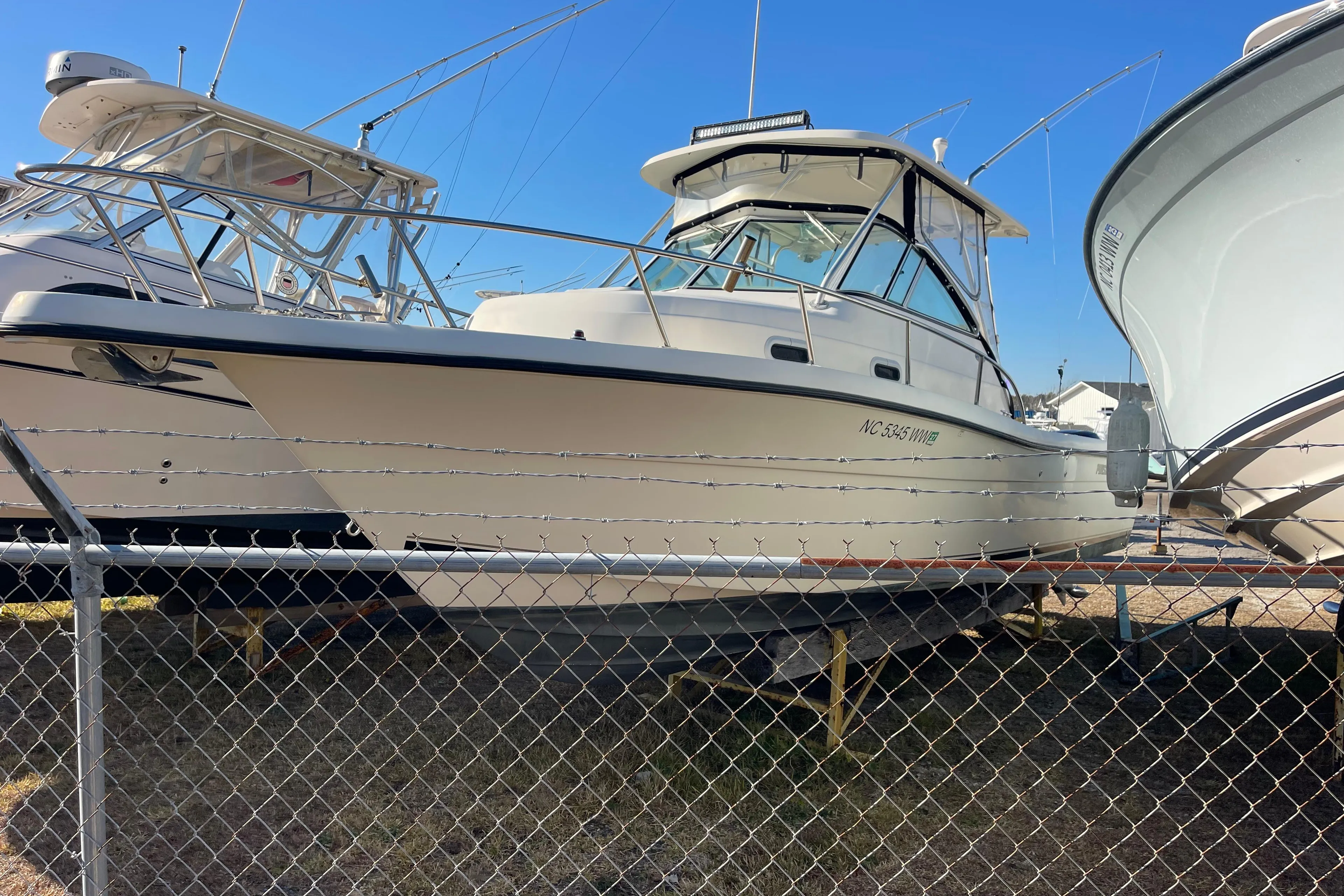 2003 Pursuit 2870 Walkaround boat on display behind a chain-link fence.