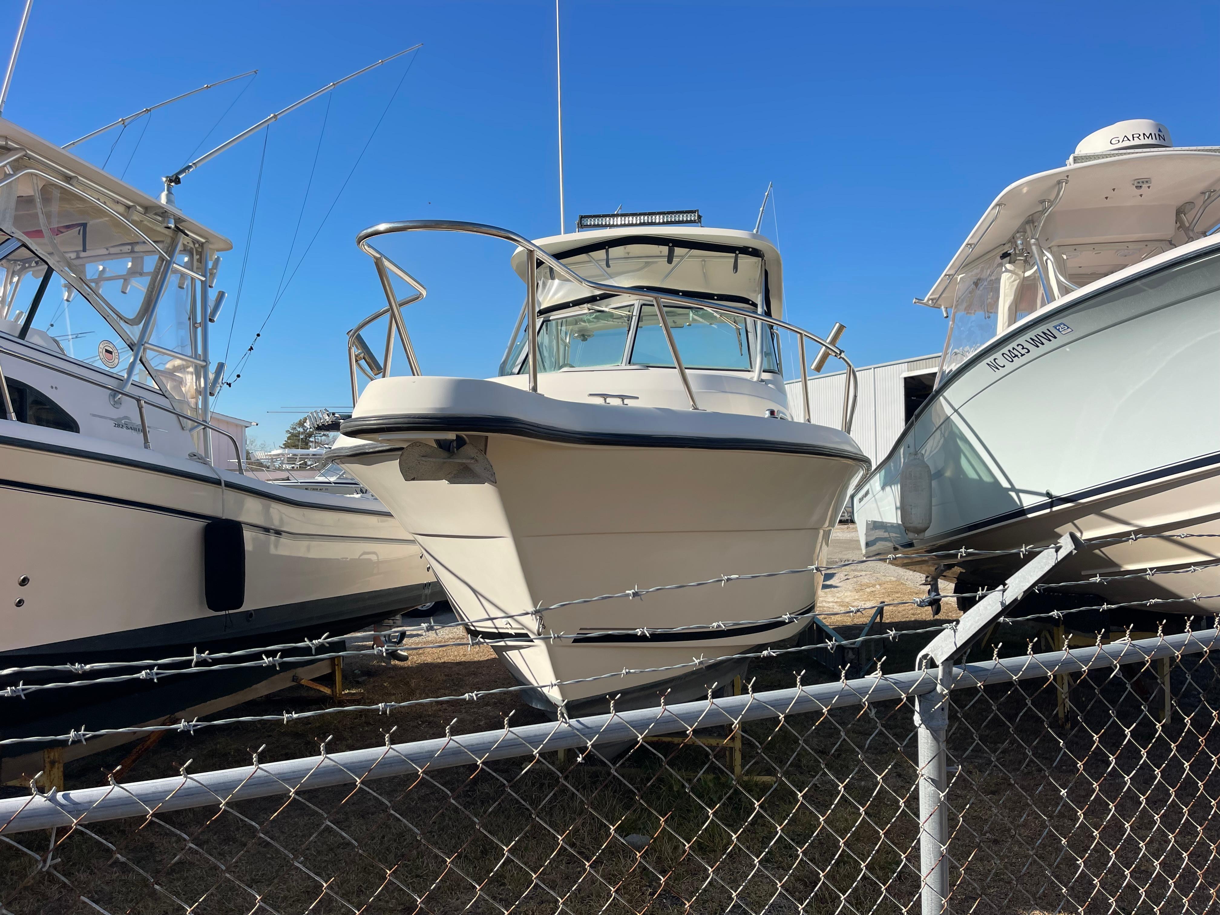 2003 Pursuit 2870 Walkaround boat displayed in a marina, surrounded by other vessels.