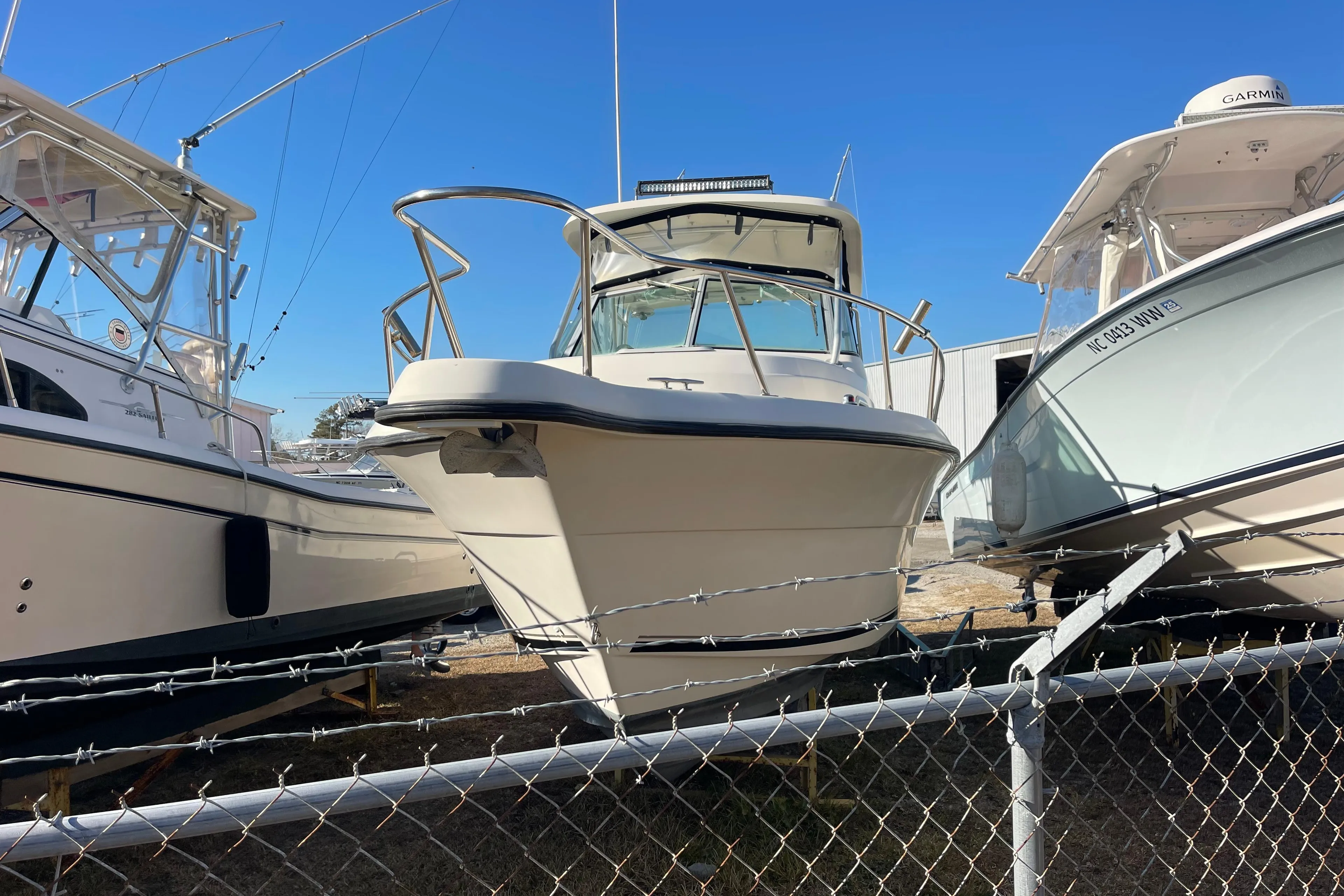 2003 Pursuit 2870 Walkaround boat displayed in a marina, surrounded by other vessels.