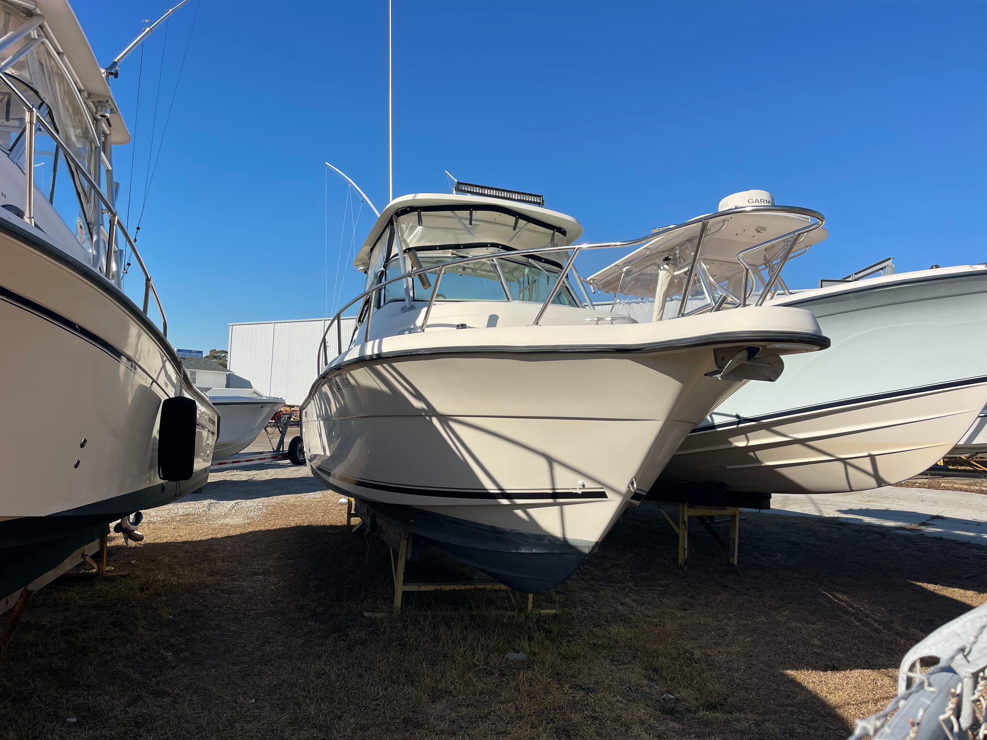2003 Pursuit 2870 Walkaround boat on display in a marina under clear blue sky.