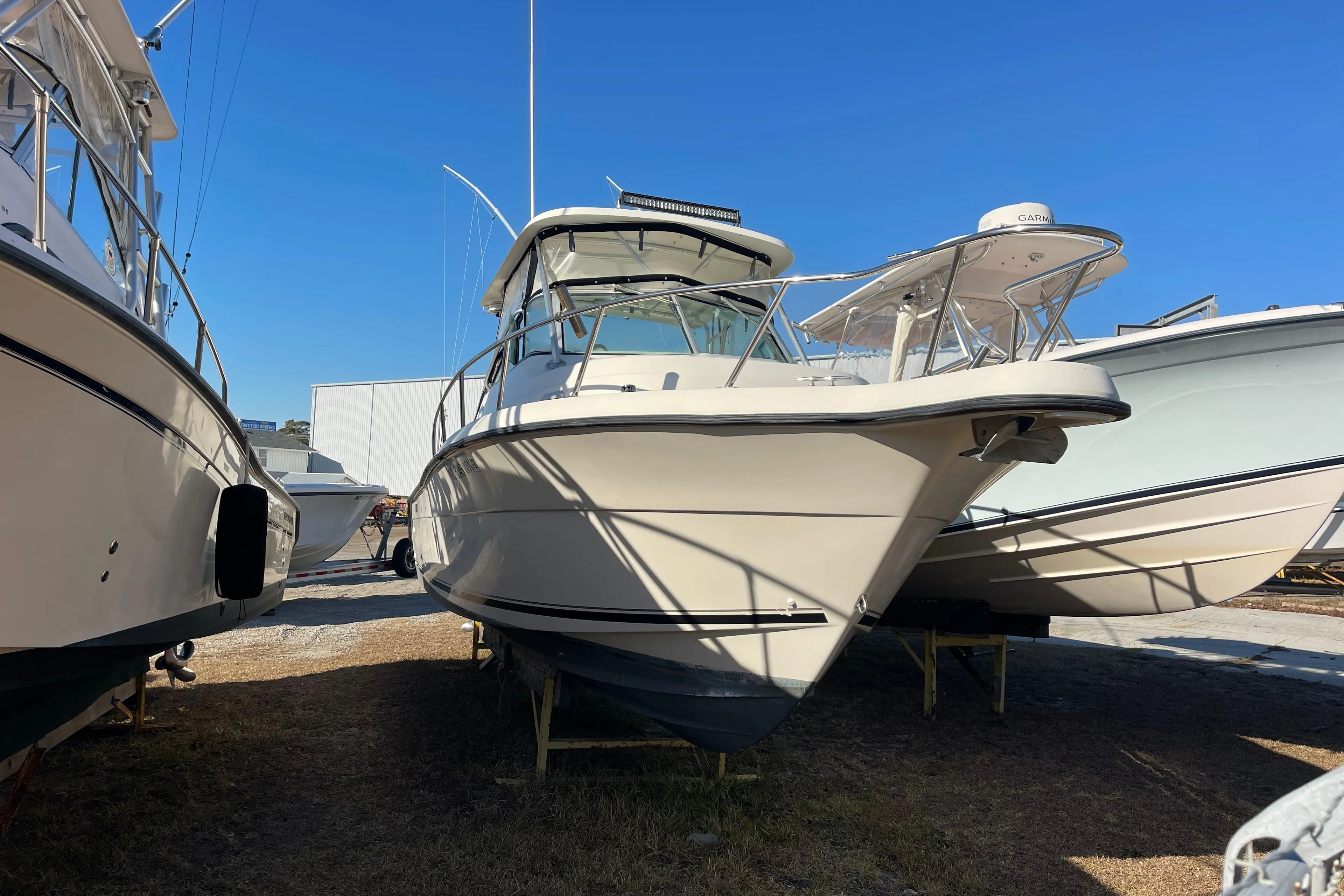 2003 Pursuit 2870 Walkaround boat on display in a marina under clear blue sky.