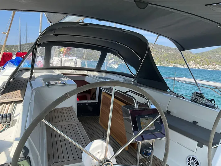 Starla Yacht Photos Pics 2012 Hanse 445 yacht cockpit with steering wheel, navigation system, and canopy, docked by the sea.