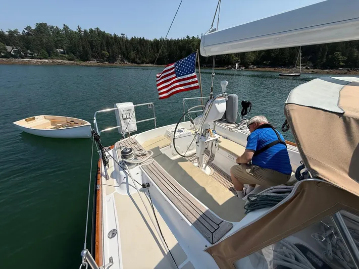 Dawn Treader Yacht Photos Pics Man on 2005 Tartan 3700 sailboat with American flag, docked in scenic waters.