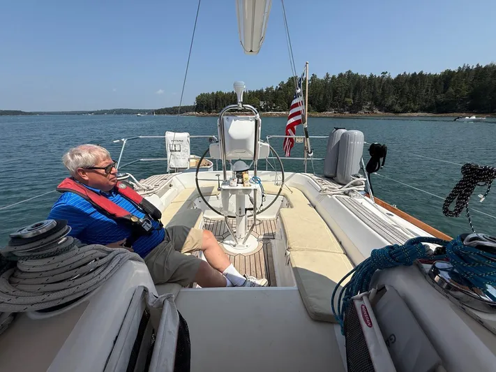 Dawn Treader Yacht Photos Pics Man relaxing on a 2005 Tartan 3700 sailboat, scenic coastal view.